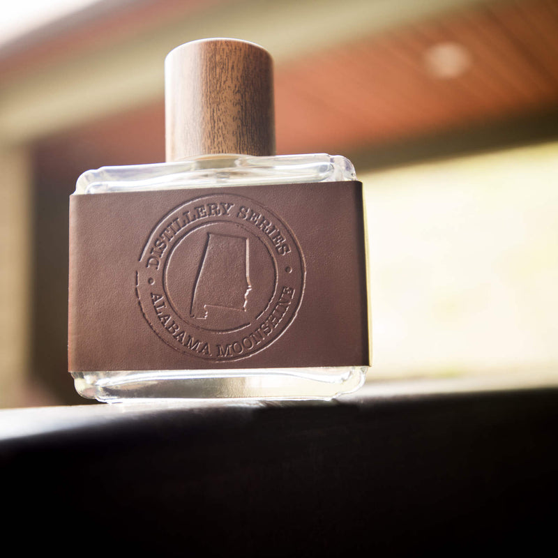 Alabama Cologne bottle in leather and wood cap inside of a Cabin