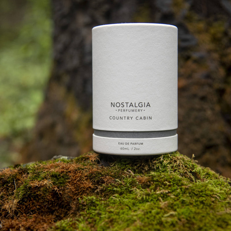 Country Cabin fragrance from Nostalgia collection in white recyclable case in the woods