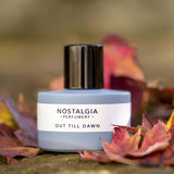 Out till Dawn Nostalgia perfume in blue grey bottle surrounded by Fall leaves