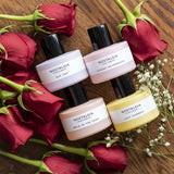 4 mini bottles of Nostalgia for a gift on red roses over a table